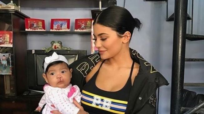 Kylie Jenner menggendong seorang balita. (Instagram)