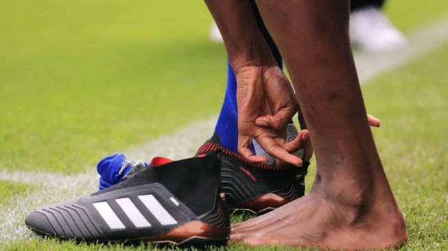 Pemain baru Barcelona Yerry Mina melepas sepatu dan kaus kakinya saat diperkenalkan di Camp Nou. Pau Barrena / AFP