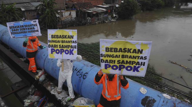 Sejumlah aktivis lingkungan hidup yang tergabung dalam Ecoton membentangkan poster ketika menggelar aksi 'jangan buang popok di Jembatan Sepanjang', Surabaya, Jawa Timur, Selasa (16/1).