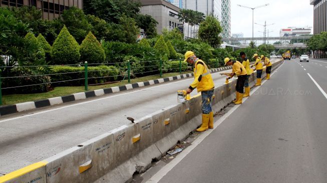 Petugas Dinas Bina Marga DKI Jakarta mengecat Movable Concrete Barrier (MCB) di jalur Transjakarta di kawasan Jalan MH Thamrin, Jakarta, Sabtu (20/1). 