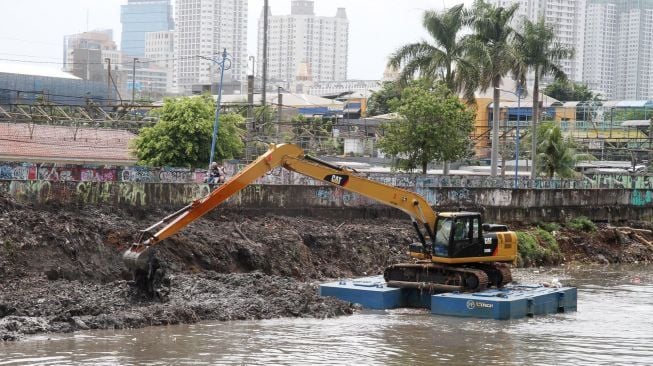 Pengerukan endapan sampah yang bercampur lumpur di aliran Kali Ciliwung, Kanal Banjir Barat, Jakarta, Selasa (20/1). 