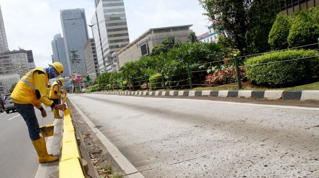 Petugas Dinas Bina Marga DKI Jakarta mengecat Movable Concrete Barrier (MCB) di jalur Transjakarta di kawasan Jalan MH Thamrin, Jakarta, Sabtu (20/1). 