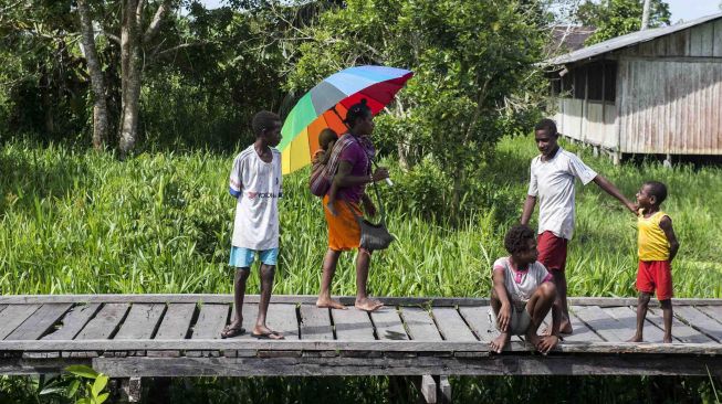 Sejumlah warga dan anak-anak menunggu speedboat di Distrik Jetsy, Kabupaten Asmat, Papua, Rabu (24/1).