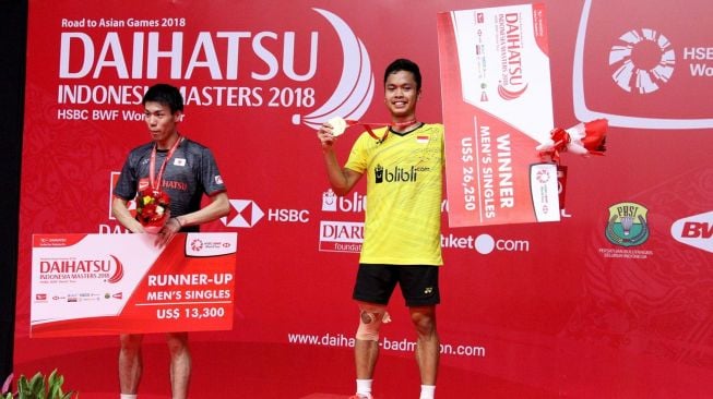 Pebulutangkis Indonesia, Anthony Sinisuka Ginting (kanan), berdiri di podium utama usai mengalahkan Kazumasa Sakai (kiri) pada final tunggal putra Indonesia Masters 2018 di Istora Senayan, Jakarta, Minggu (28/1). [Humas PBSI]