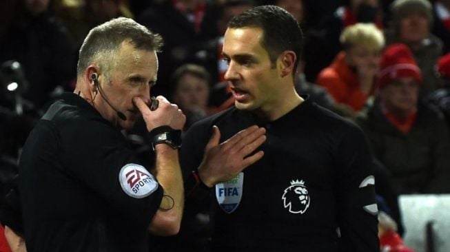 Wasit pemimpin laga antara Liverpool vs Tottenham Hotspur, John Moss (kiri), berdiskusi dengan hakim garis soal pelanggaran Virgil van Dijk terhadap Erik Lamela [AFP]