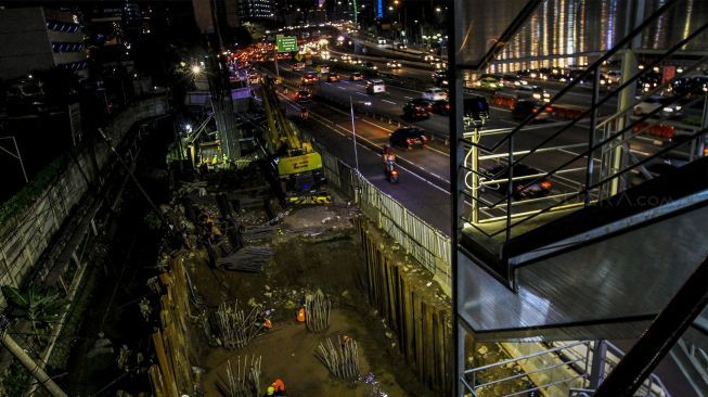 Sejumlah kendaraan melintas di samping lokasi proyek pembangunan Light Rail Transit (LRT) di Jalan Gatot Subroto, Jakarta (6/2) malam. 