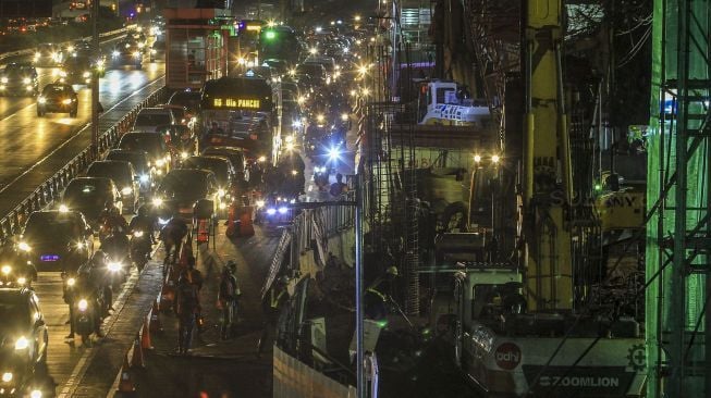 Sejumlah kendaraan melintas di samping lokasi proyek pembangunan Light Rail Transit (LRT) di Jalan Gatot Subroto, Jakarta (6/2) malam. 