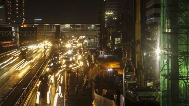 Sejumlah kendaraan melintas di samping lokasi proyek pembangunan Light Rail Transit (LRT) di Jalan Gatot Subroto, Jakarta (6/2) malam. 