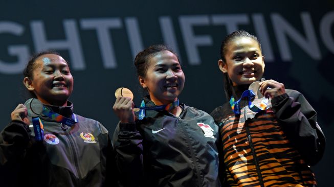 Lifter Indonesia Dewi Safitri (tengah) bersama Syarah Anggraini (kiri) dan lifter Malaysia Sharifah Inani menunjukkan medali yang mereka terima di nomor putri 53 kg A di Test Event Asian games 2018. ANTARA FOTO/Fanny Octavianus