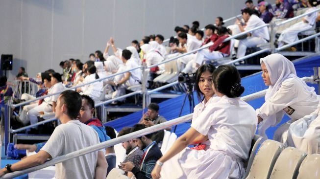 Puluhan siswa-siswi dari SMA 80 Sunter, Jakarta Utara, menyemarakkan hari kedua penyelenggaraan test event Asian Games 2018 cabang angkat besi di JIExpo Hall A1 Kemayoran, Jakarta Pusat, Senin (12/2). [Suara.com/Dendi Afriyan]