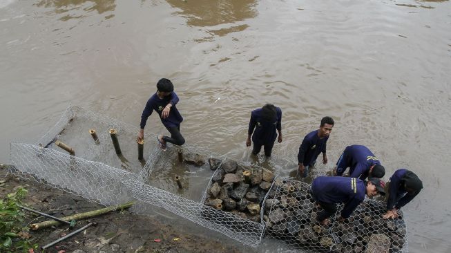 Petugas Sudin Bina Marga dan Sudin Tata Air dan PPSU melakukan pemasangan bronjong kawat di lokasi terjadinya jalan retak sepanjang 50 meter di Kampung Berlan, Matraman, Jakarta, Rabu (14/2).