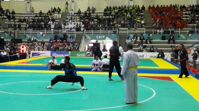 Pesilat Indonesia, Eko Febrianto (sabuk biru), mengalahkan pesilat Malaysia, Mohd Khaizul bin Yaacob, pada final Kelas J Pencak Silat Test Event Asian Games 2018 di Padepokan Pencak Silat, Taman Mini, Kamis (15/2). [Suara.com/Rizki Nurmansyah]