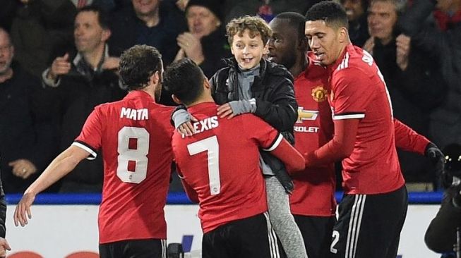 Para pemain Manchester United merayakan gol bersama seorang suporter cilik yang masuk ke lapangan (AFP/Oli Scarff)