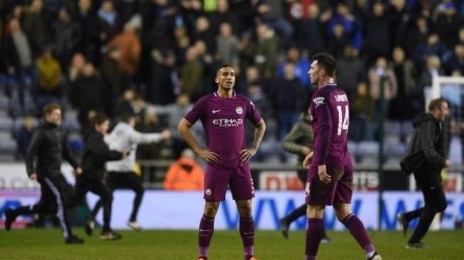 Reaksi pemain Manchester City Danilo (kiri) dan Aymeric Laporte setelah fans Wigan Athletic masuk ke dalam lapangan usai pertandingan. Oli SCARFF / AFP