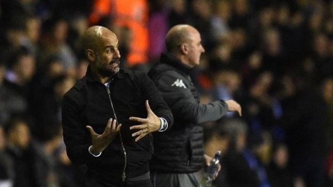 Reaksi manajer Manchester City Pep Guardiola (kiri) dan manajer Wigan Athletic Paul Cook di pinggir lapangan. Oli SCARFF / AFP
