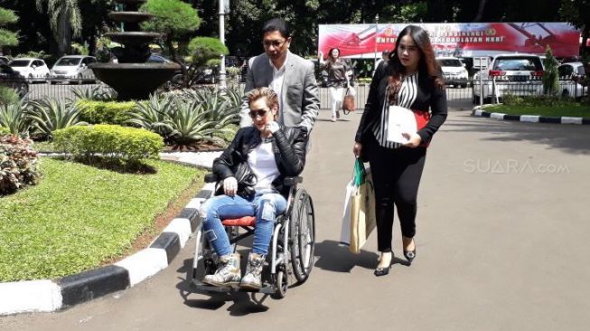 Menggunakan kursi roda dan didampingi pengacara serta ibu, Melodya Vanesha mendatangi Polda Metro Jaya. (Wahyu Tri Laksono/Suara.com)