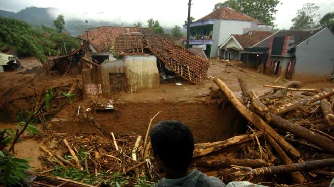 Seorang warga memperhatikan pemukiman yang terkena banjir material longsor di Desa Pasirpanjang, Salem, Brebes, Jawa Tengah, Jumat (23/2). 