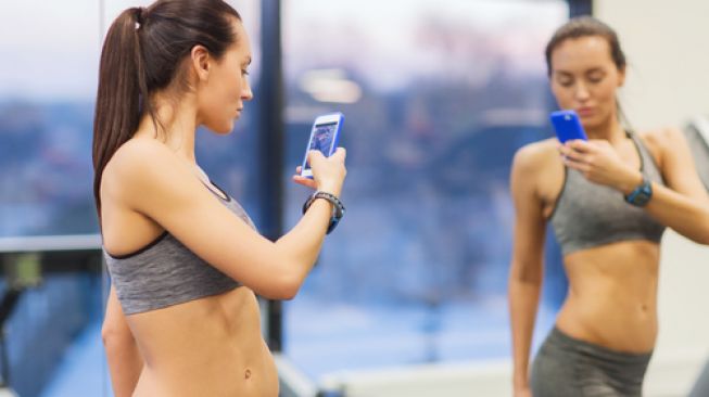 Seorang perempuan sedang asyik selfie atau swafoto di gym. (Shutterstock)