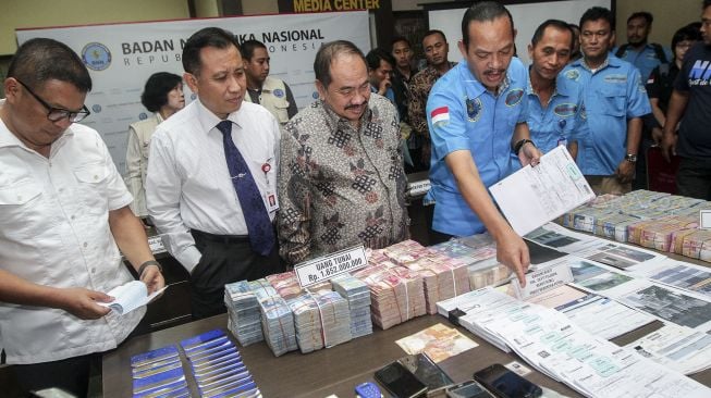 Deputi Pemberantasan Badan Narkotika Nasional (BNN) Irjen (Pol) Arman Depari bersama sejumlah pejabat terkait dari PPATK, Mabes Polri, OJK dan Bank Indonesia, menunjukkan barang bukti hasil pengungkapan kasus tindak pidana pencucian uang (TPPU) dari kasus narkotika di Jakarta, Rabu (28/2/2018). [Suara.com/Kurniawan Mas'ud]