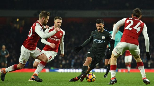 Pemain Man City Sergio Aguero mencoba melewati tiga pemain Arsenal [AFP]