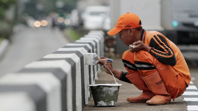 Petugas Penanganan Prasarana dan Sarana Umum (PPSU) DKI Jakarta mengecat trotoar pembatas jalan di Jalan Jatinegara, Jakarta, Jumat (2/3).