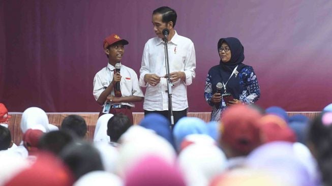 Presiden Joko Widodo (tengah) berdialog dengan seorang siswa dan guru saat penyerahan Kartu Indonesia Pintar dan Program Keluarga Harapan di Gor Tri Dharma, Gresik, Jawa Timur, Kamis (8/3).