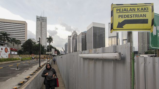 Pejalan kaki melintasi pedestrian di area perkantoran di kawasan Jalan Sudirman, Jakarta, Jumat (9/3). 