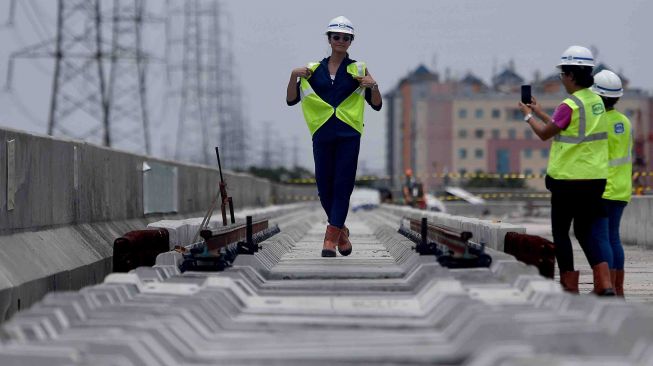 Model Kelly Tandiono (kiri) berpose di atas bantalan rel proyek pembangunan infrastruktur depo Light Rail Transit (LRT) di Kelapa Gading, Jakarta, Sabtu (10/3).