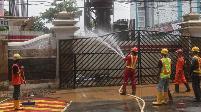 Sejumlah pekerja membersihkan sisa semburan lumpur gas PGN yang bocor di halaman kantor Badan Narkotika Nasional (BNN) di Cawang, Jakarta, Selasa (13/2). 