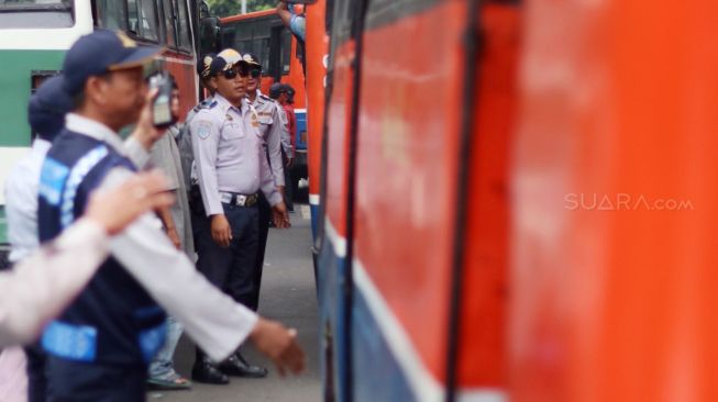 Petugas memeriksa kelengkapan surat kendaraan Metromini dan Kopaja saat razia angkutan umum di Jalan Sudirman, Jakarta, Selasa (13/3). 