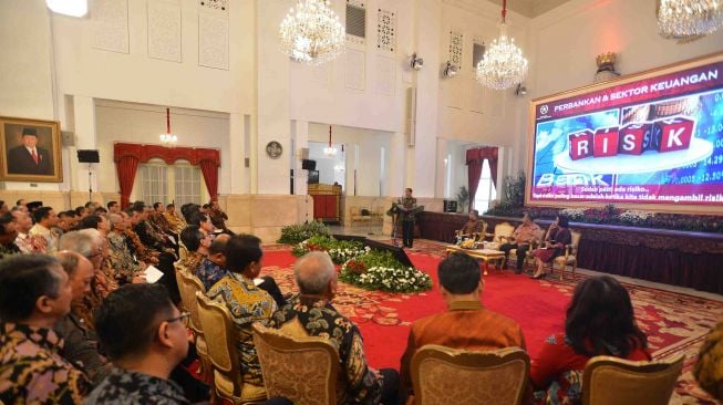 Presiden Joko Widodo (kiri) didampingi Menko Perekonomian Darmin Nasution (kedua kanan), Menkeu Sri Mulyani (kanan) dan Ketua Dewan Komisioner Otoritas Jasa Keuangan Wimboh Santoso (kedua kiri) menyampaikan paparan dihadapan pimpinan bank umum di Indonesia, di Istana Negara, Jakarta, Kamis (15/3). 