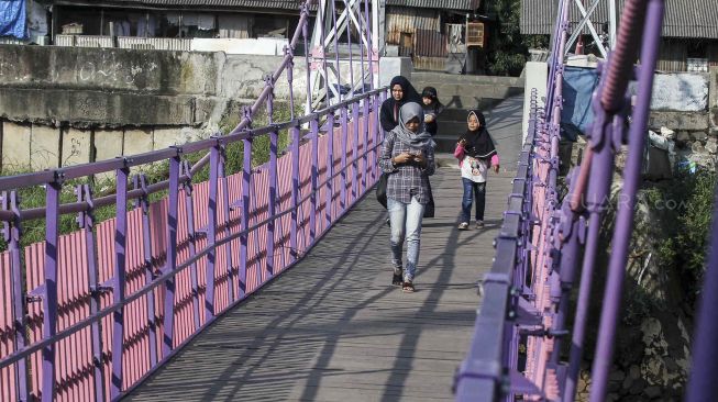 Warga melintas di Jembatan Gantung baru di Jati Pulo, Jakarta, Selasa (20/3).