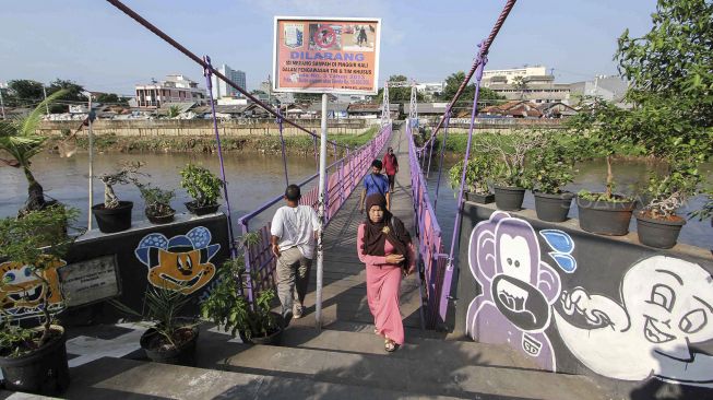 Warga melintas di Jembatan Gantung baru di Jati Pulo, Jakarta, Selasa (20/3).