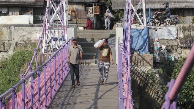 Warga melintas di Jembatan Gantung baru di Jati Pulo, Jakarta, Selasa (20/3).