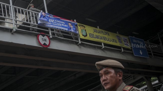 Petugas Satpol PP bersama dengan petugas Bawaslu menertibkan sejumlah spanduk dan atribut partai politik yang dipasang di sepanjang Jalan Letjen Suprapto dan Ahmad Yani, Cempaka Putih, Jakarta, Rabu (21/3). 