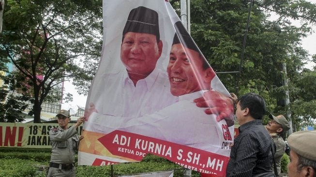 Petugas Satpol PP bersama dengan petugas Bawaslu menertibkan sejumlah spanduk dan atribut partai politik yang dipasang di sepanjang Jalan Letjen Suprapto dan Ahmad Yani, Cempaka Putih, Jakarta, Rabu (21/3). 