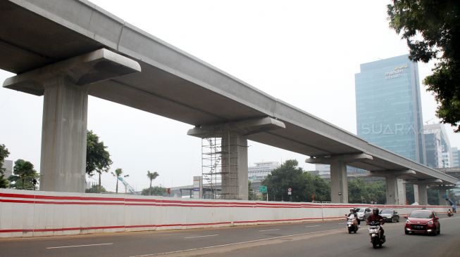 Pekerja menyelesaikan pembangunan proyek kereta ringan atau light rail transit Jakarta-Bogor-Depok-Bekasi (LRT Jabodebek) di kawasan Kuningan, Jakarta, Jumat (24/3/2018). [Suara.com/Oke Atmaja]