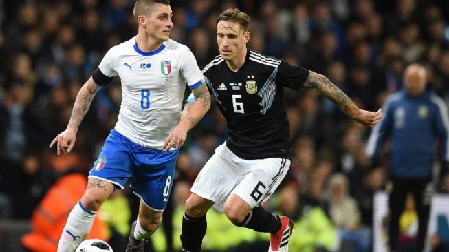 Gelandang Timnas Italia, Marco Verratti (kiri) mendapat pengawalan ketat dari gelandang Timnas Argentina, Lucas Biglia saat timnya kalah 2-0 dalam laga persahabatan di Etihad Stadium, Manchester, Inggris, Jumat (23/3/2018). [AFP/Oli Scarff]