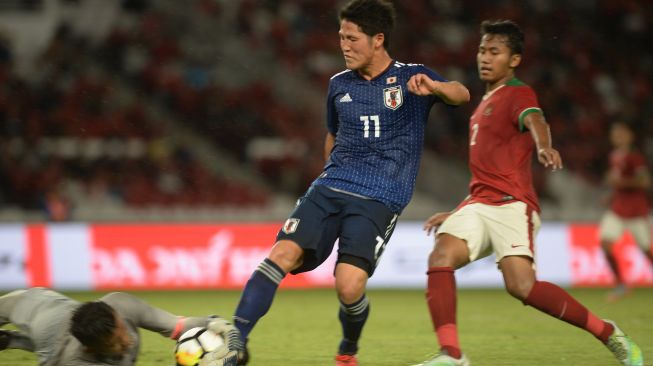 Penjaga gawang Timnas U-19 M Aqil Savic (kiri) memblok bola tendangan pesepak bola Jepang U-19 Ando Mizuki (tengah) dalam laga persahabatan di Stadion Utama Gelora Bung Karno, Jakarta, Minggu (25/3). Indonesia kalah dari Jepang dengan skor akhir 1-4. ANTARA