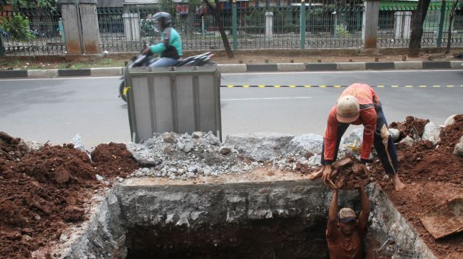 Pekerja meyelesaikan proyek pembuatan lubang resapan air di kawasan Patal Senayan, Jakarta, Senin (26/3).