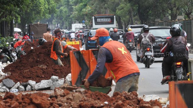 Pekerja meyelesaikan proyek pembuatan lubang resapan air di kawasan Patal Senayan, Jakarta, Senin (26/3).