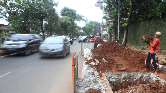 Pekerja meyelesaikan proyek pembuatan lubang resapan air di kawasan Patal Senayan, Jakarta, Senin (26/3).