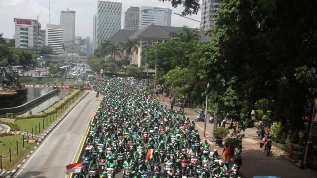 Ribuan driver ojek online (Ojol) berunjuk rasa di Jalan Medan Merdeka, Jakarta, Selasa (27/3).