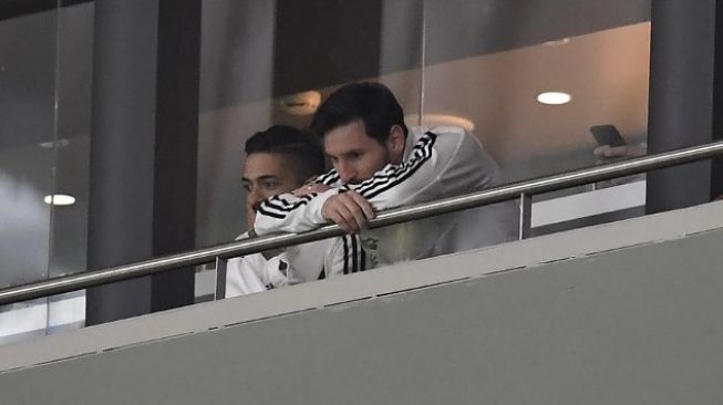 Bintang Argentina Lionel Messi (kanan) di bangku penonton menyaksikan skuatnya kalah dari Spanyol 6-1 di Wanda Metropolitano. GABRIEL BOUYS / AFP 