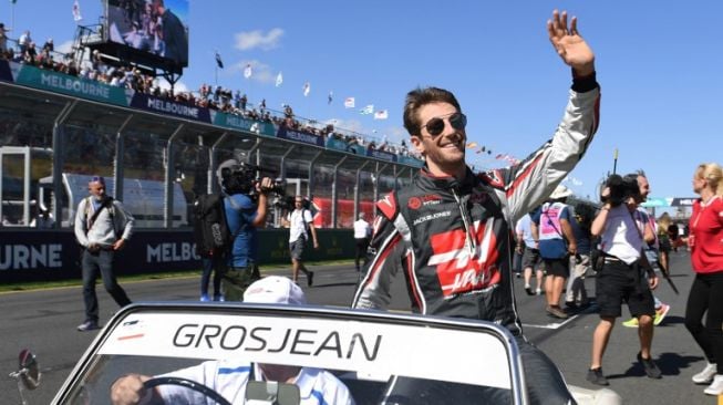 Pebalap tim Haas, Romain Grosjean melambaikan tangan ke penonton dalam parade jelang balap F1 GP Australia di Sirkuit Albert Park, Minggu (25/3/2018). [AFP/Saeed Khan]