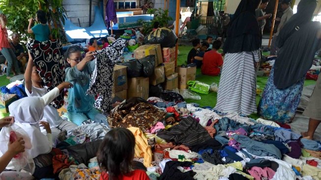 Warga memilah baju yang masih bisa digunakan di tenda pengungsi korban kebakaran kawasan Taman Kota, Kembangan, Jakarta, Sabtu (31/3). 