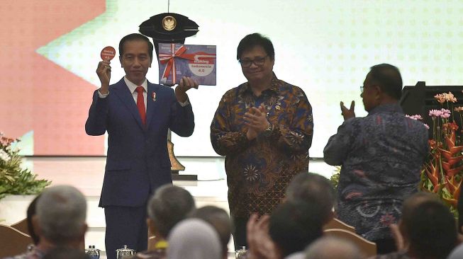 Presiden Joko Widodo (kiri) didampingi Menteri Perindustrian Airlangga Hartarto (kedua kanan) dan Menko Perekonomian Darmin Nasution (kanan) menunjukkan buku serta pin Making Indonesia 4.0 usai pembukaan Industrial Summit 2018 di Jakarta, Rabu (4/4). 