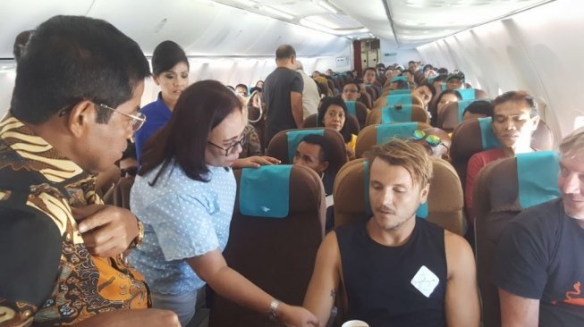 Mensos, Idrus Marham memberikan pertolongan kepada satu wisatawan manca negara di pesawat Garuda Indonesia. (Sumber: Istimewa)