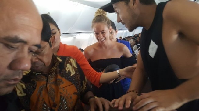 Mensos, Idrus Marham memberikan pertolongan kepada satu wisatawan manca negara di pesawat Garuda Indonesia. (Sumber: Istimewa)