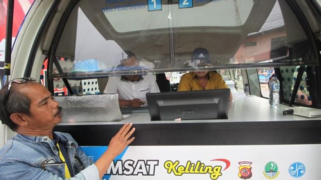 Seorang konsumen membayar pajak kendaraan di Samsat keliling di Bandung belum lama ini. Dengan BJB T-Samsat, masyarakat kini tak perlu antre dan telat lagi dalam membayar pajak kendaraan. (Sumber: Istimewa)